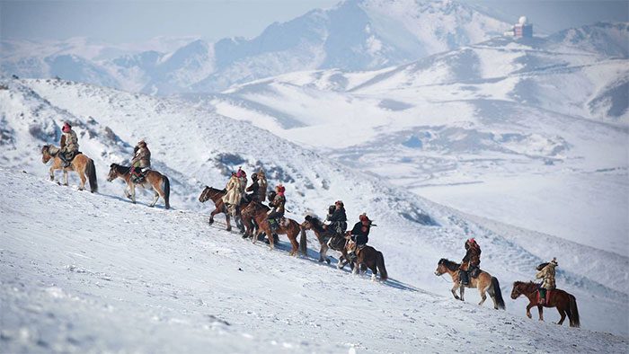 People riding horses with eagles on their shoulders during the Spring Eagle Festival in Ulaanbaatar