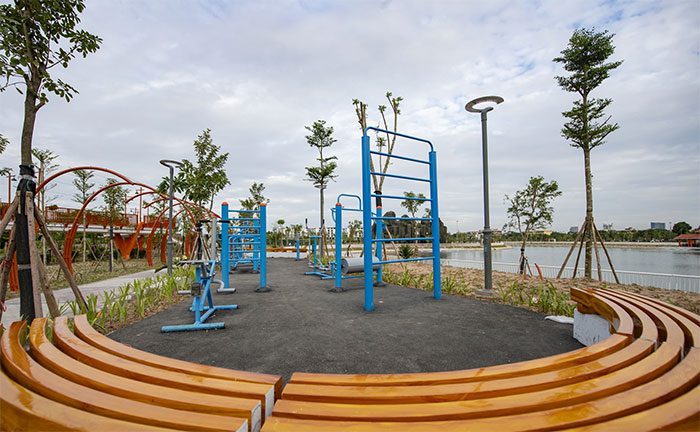 Various public exercise and sports equipment are arranged around the park.