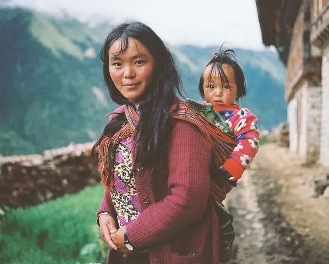 A woman in Laya carrying her daughter on her back.
