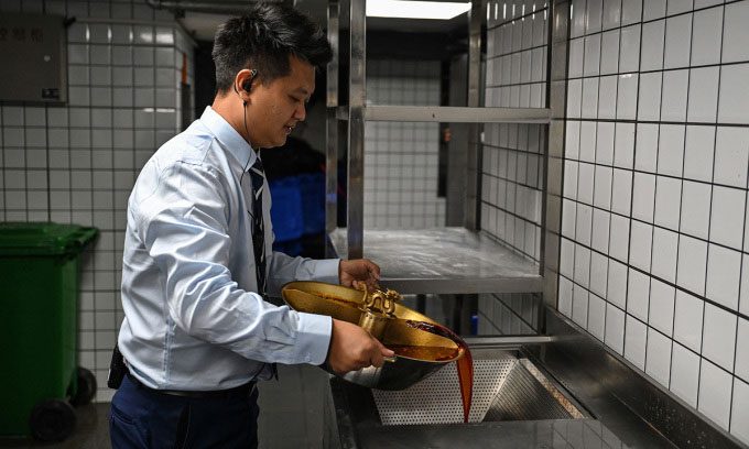 Restaurant staff in Chengdu pouring hot pot broth mixed with oil into a filter funnel for recycling.