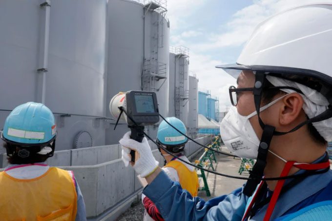 TEPCO representatives measuring radiation levels around treated water storage tanks