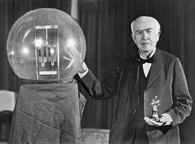 Thomas Edison holds a light bulb at a party in New Jersey, USA