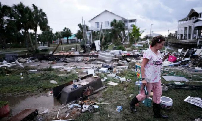 A woman walking among the rubble in Horseshoe Beach, Florida