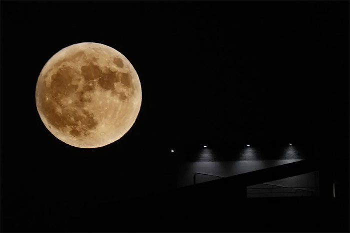 The full Moon rising next to a spotlight from a building in Beirut, Lebanon