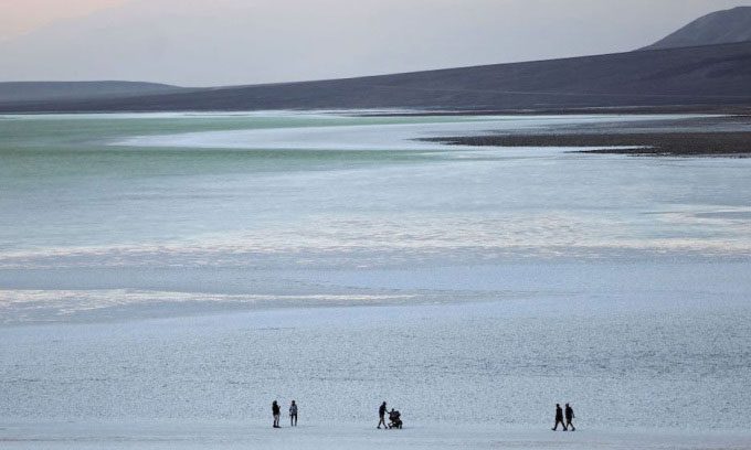 Visitors walking along the rare lake that formed in Death Valley after Hurricane Hilary.