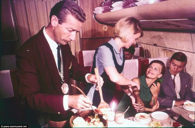 A flight attendant sprinkling pepper for a customer