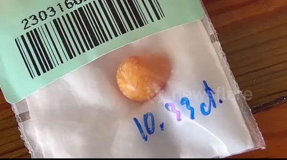 The orange object found by the man in Thailand is a genuine pearl and very valuable.