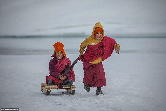 Two monks enjoying a moment of relaxation by riding a sled