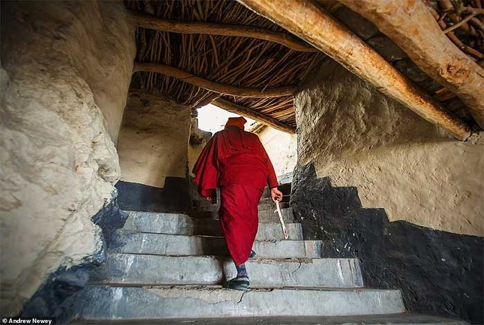 A monk climbs several steps to the rooftop to pray early in the morning at Phugtal Monastery.