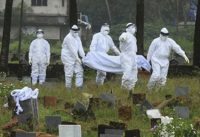 Healthcare workers in protective gear cremating the body of a 12-year-old boy infected with the Nipah virus in Kerala