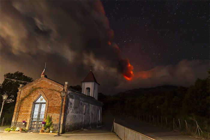 View of Mount Etna erupting from a church in Sicily.