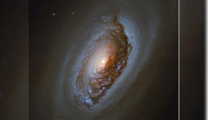 Messier 64, nicknamed the "Black Eye Galaxy," is obscured by a dark dust lane covering its central region.