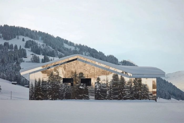 The house reflects and interacts with the mountain landscape through changing seasons.