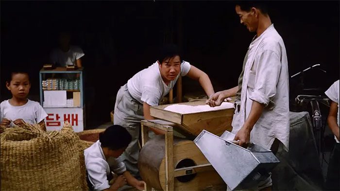 A rice seller next to his rice milling machine