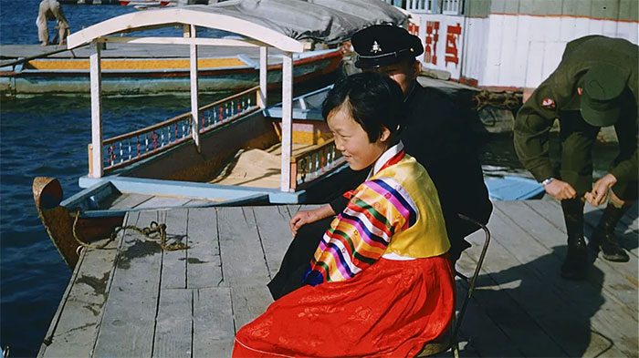 A young girl sitting by the Han River in a vibrant hanbok
