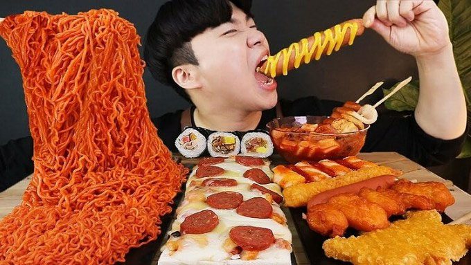 A person consuming a large quantity of food while recording themselves and interacting directly with viewers.