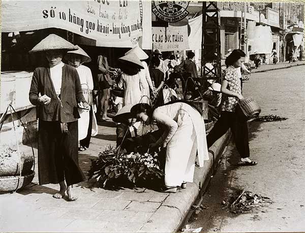 Flower vendors on the sidewalk near Đồng Xuân Market in 1951.