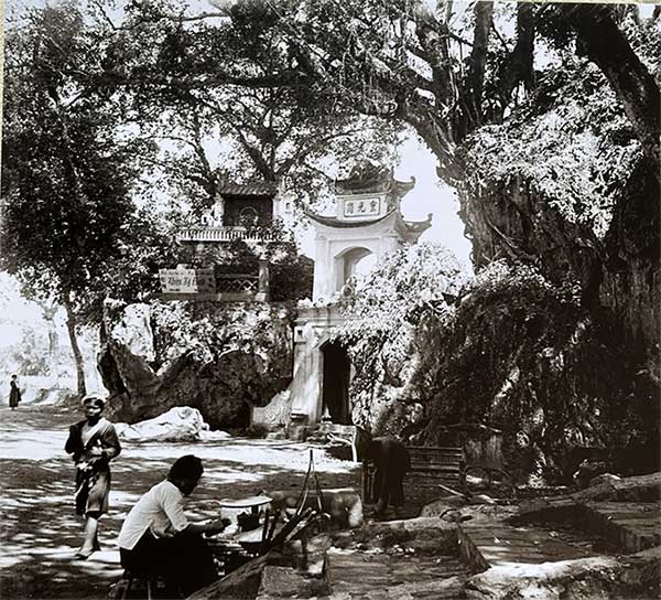 A vendor selling sugarcane in front of a temple before 1915