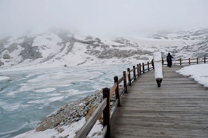 A person carrying a roll of white fabric to cover the glacier