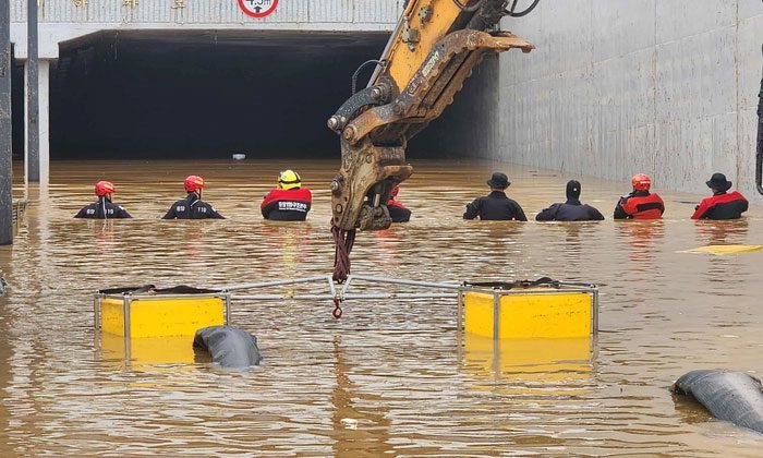 Rescue teams wade through an underground tunnel searching for trapped individuals