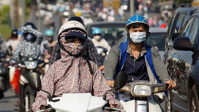 Pedestrians wearing full sun protection while outside.