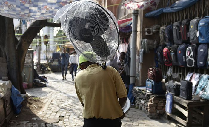 In the image, a man carries a fan during a heatwave in Kolkata, India.
