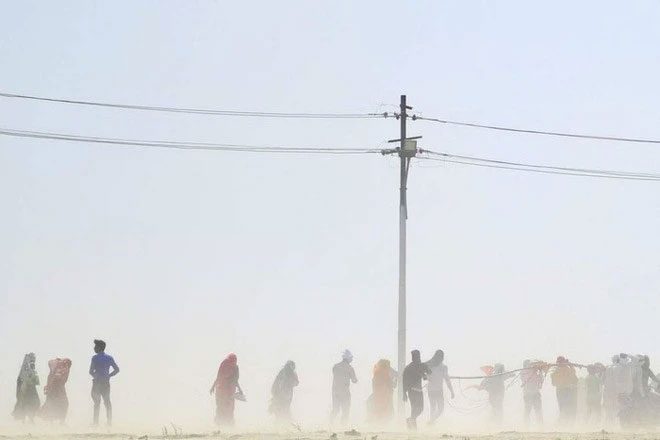 People walking through a dust storm on a hot summer day in Prayagraj