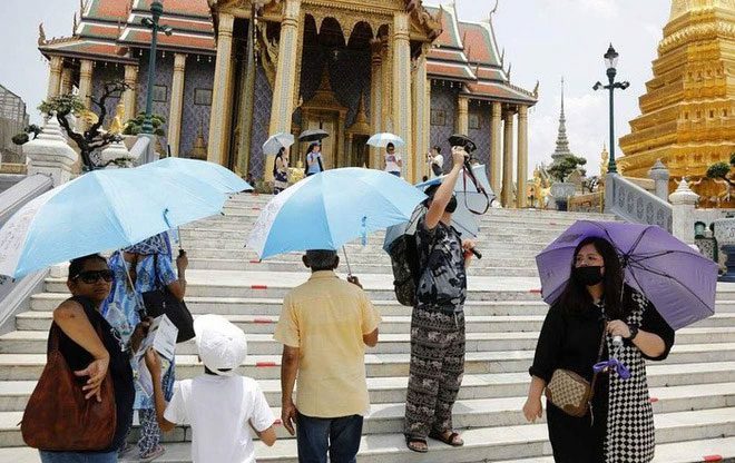 People using umbrellas to shield themselves from the heat while traveling in Thailand