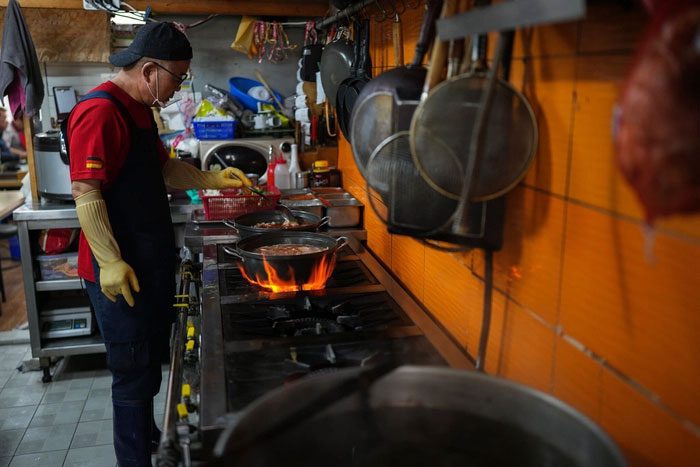 Lee Hae-yeon cooking at the restaurant. Leftovers are collected in a bin.