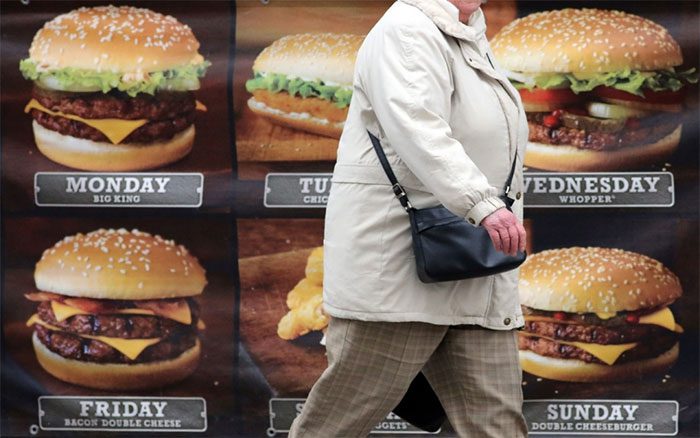 A woman passing a fast food advertisement in Bristol, UK