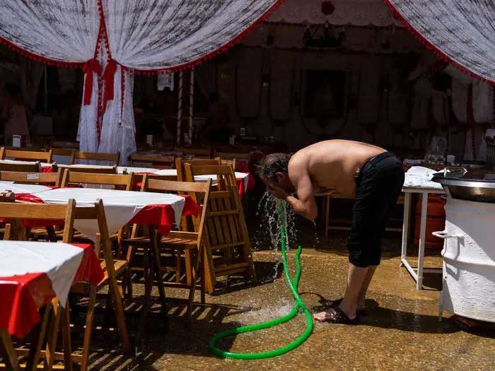 A man cooling off with water outside a "caseta"