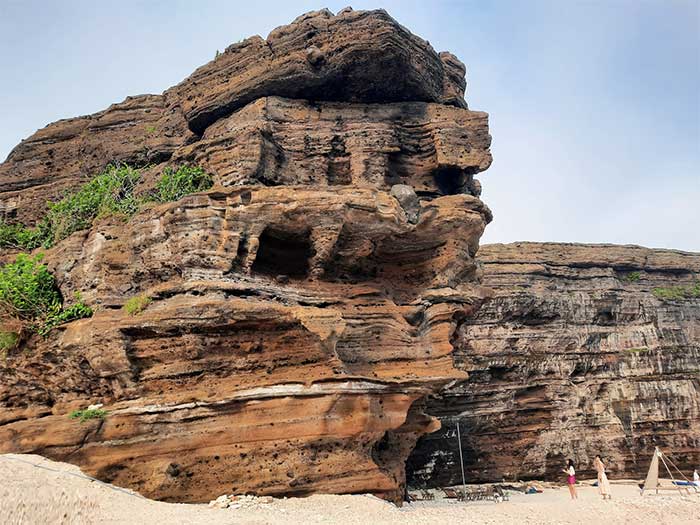 A portion of the cliff extends into the sea, shaped uniquely by wave erosion.