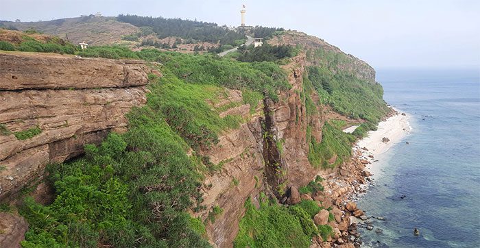 Above the cliff is the path leading to the crater of Thoi Loi Volcano and the national flagpole.