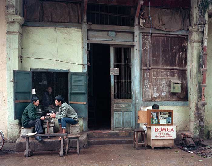 Two men drinking tea next to a gas lighter stand at 8 Ly Thai To Street in 1988.