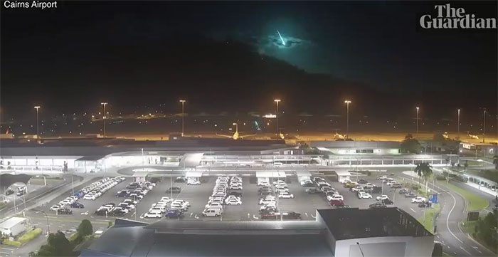 A large fireball descends to the ground, followed by flashes of green and blue light.