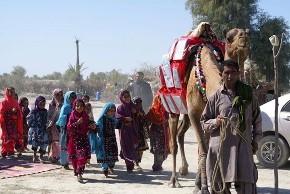 Children greet Roshan the camel.