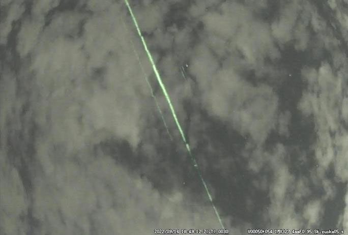 Laser beam flying through the cloudy sky near Mount Fuji