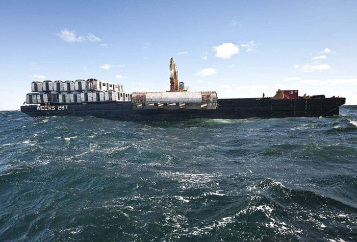 Images of subway cars being taken out to sea and dropped.
