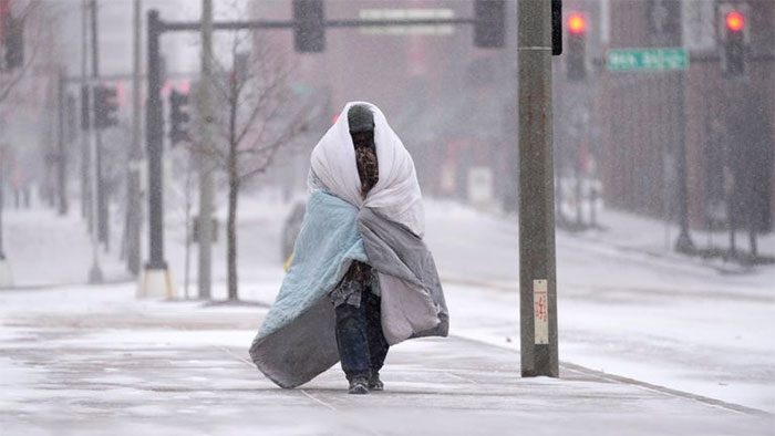 A man wrapped in a blanket while moving outside during snowfall in St. Louis, Missouri