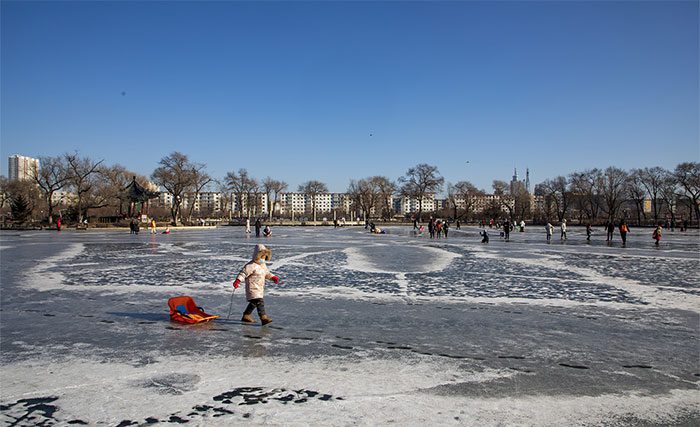 Visitors ice skating on a thick frozen lake in Beishan Park.