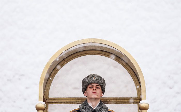 A soldier standing solemnly in the snow in Moscow.