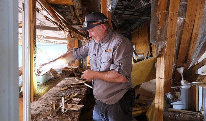 Chris Cook peeling the remaining wood from the frame at the restaurant to check for termite damage.