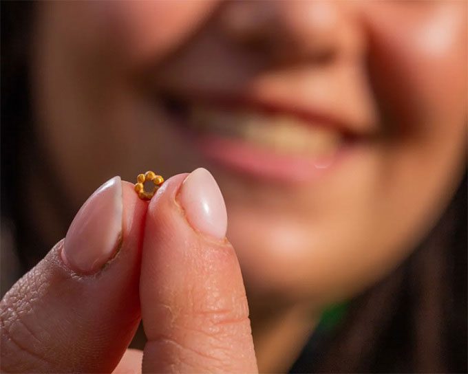 Hallel Feidman holding the tiny pure gold bead necklace.