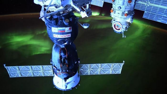 Russian Soyuz spacecraft and aurora in the background.