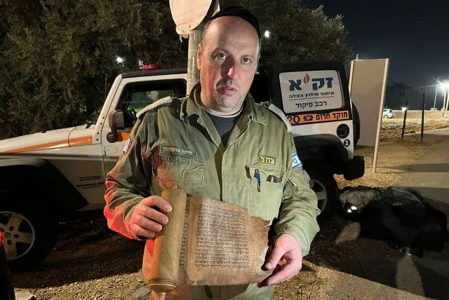 Lieutenant Colonel Haim Otmazgin holding the ancient Book of Esther.