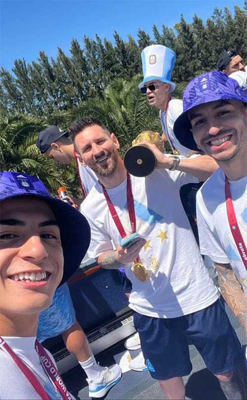 Messi carries the trophy on his shoulder, taking a selfie with two teammates