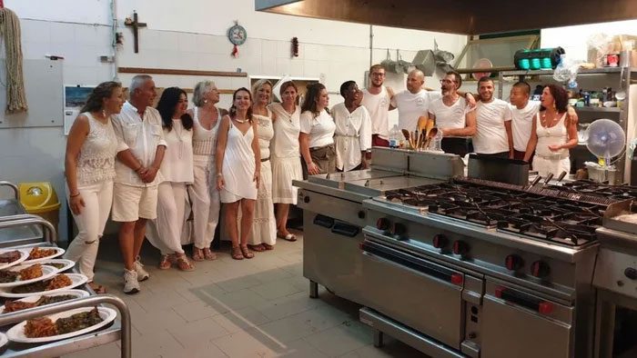 Tourists taking photos with male inmates working as hotel staff in Pianosa.