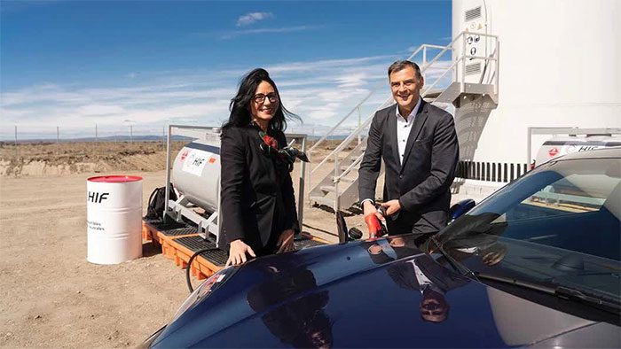 Porsche executives refueling a Porsche 911 with green gasoline.