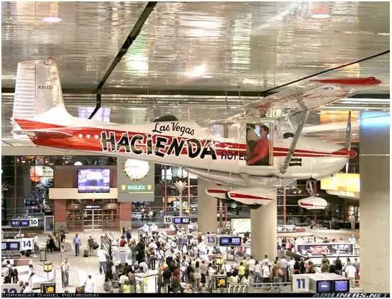 The aircraft is mounted on the ceiling in the baggage claim area at McCarran Airport.