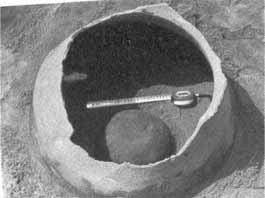 Typical Sa Huỳnh burial jar made of earthenware. The photo shows the jar being discovered, still buried in the ground, with a broken mouth and burial items inside.